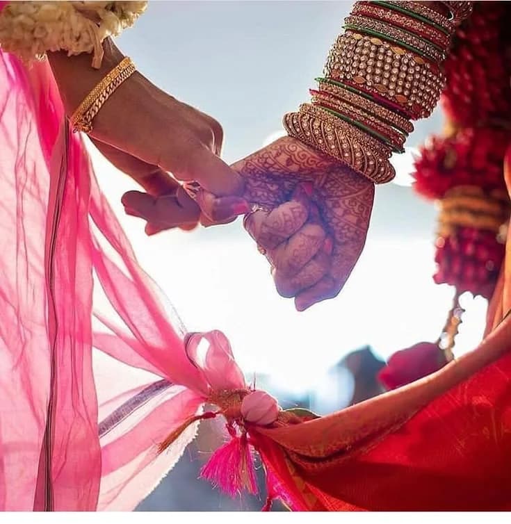 மணமக்கள் கைகோர்த்து நிற்கும் பாரம்பரிய திருமணக் காட்சி